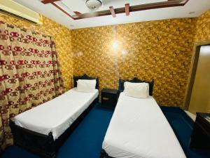 two beds in a small room with yellow wallpaper at Lux Lodges Guest House in Islamabad