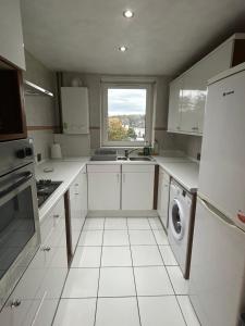 cocina con armarios blancos, ventana y lavavajillas en Spacious 3 Bedroom Flat, en Edimburgo