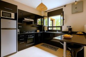 - une cuisine avec des armoires noires et un réfrigérateur blanc dans l'établissement Appartement Luxe 2 Chambres Vue Directe Jardin Majorelle YSL, à Marrakech