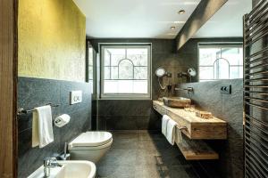 a bathroom with a toilet and a sink and a mirror at Hotel Tyrol in Malles Venosta
