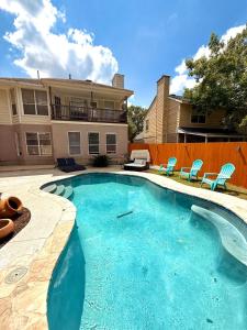 a swimming pool with blue chairs and a house at Minutes from Sea World and Fiesta Texas in San Antonio