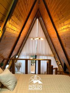 a bed in a room with a wooden ceiling at Chales alto do morro 1, conforto e vista privilegiada in Rancho Queimado