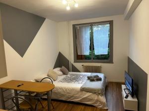 a bedroom with a bed and a table and a window at Studio 29 in Troyes