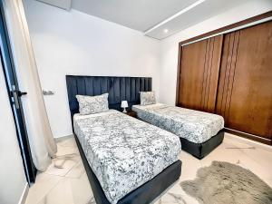 a bedroom with two beds and a wooden door at Centre-ville - bien équipé - Neuf - WiFi - Calme in Kenitra