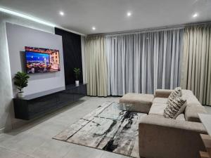 a living room with a couch and a flat screen tv at Home Sweet Luxe Stays in Lobamba