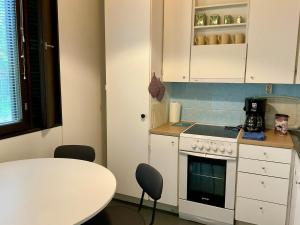 eine Küche mit Herd und Tisch mit Stühlen in der Unterkunft Studio Sulkava - Cozy studio with sauna and yard in Sulkava