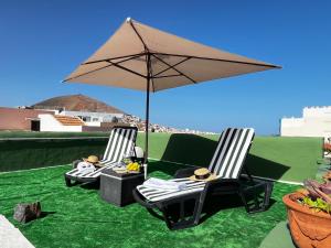 two chairs and an umbrella on a lawn at Aloe Apartament 2 plus 1 gratis w Casa Verde de Guía in Santa Maria de Guia de Gran Canaria