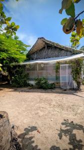 a building with a thatched roof and a dirt yard at Casa Corazón in El Cuyo