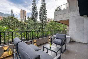 einen Balkon mit Sofa und Stühlen auf einem Gebäude in der Unterkunft Morph 401 - Modern apt High Ceilings BBQ/Jacuzzi in El Poblado