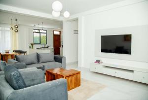 een woonkamer met een bank en een tv bij Smile Apartments Arusha in Arusha