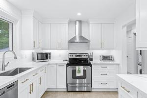 a white kitchen with a stove and a sink at Charming 3-Bed House with Hot Tub close to Downtown in Barrie