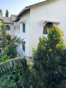 un bâtiment blanc avec des arbres devant dans l'établissement Raine house, à Ukunda 3 autres photos
