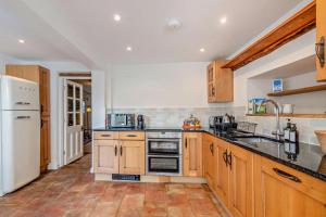 a kitchen with wooden cabinets and a white refrigerator at Bakers Cottage - Sidestrand in Sidestrand +11 photos