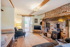 a living room with a brick wall and a fireplace at Bakers Cottage - Sidestrand in Sidestrand