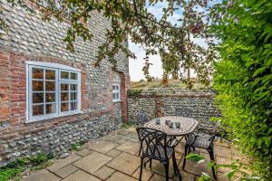 a patio with a table and chairs in front of a brick building at Bakers Cottage - Sidestrand in Sidestrand