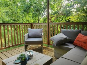 a patio with a couch and a chair on a deck at Lodge à Folie Verte in Fontenay-le-Comte