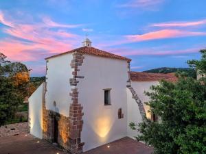 a church with a sunset in the background at S'apposentu 'e Santa Ruche in Oniferi