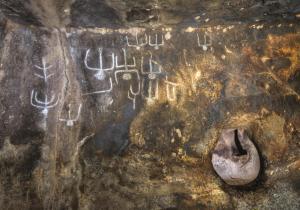 a rock with writing on it with a urinal at S'apposentu 'e Santa Ruche in Oniferi