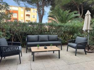 drie stoelen en een bank en een tafel en een parasol bij LAGON BLEU - Proche Gare Routière - Terrasse & Piscine - 3Km PLAGE - PARKING & WIFI Gratuit - OFFRE SPECIALE in Fréjus