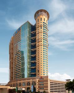 a tall building with a round tower on top of it at Grand Millennium Al Wahda Hotel and Executive Apartments Abu Dhabi in Abu Dhabi