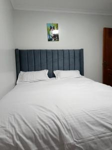 a large bed with white sheets and pillows at Qara Homes One Bedroom, Juja in Juja