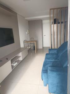 a living room with a blue bed and a tv at Edifício Concept in Marília