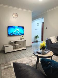 a living room with a couch and a tv at Qara Homes One Bedroom, Juja in Juja