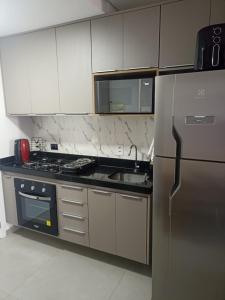 a kitchen with a stainless steel refrigerator and a sink at Edifício Concept in Marília