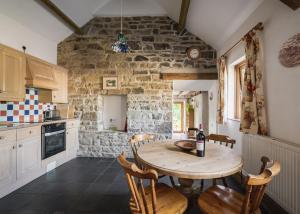 une cuisine avec une table et des chaises dans une pièce dans l'établissement Cove Cottage, à Llandysul