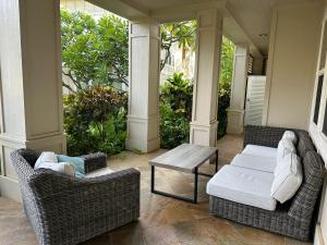 un porche con 2 sillas de mimbre y una mesa en Ground Floor Luxury Penthouse in Poipu Kai, en Koloa