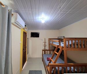 a room with two bunk beds and a television at Pontal Hostel FLAT ilheus in Ilhéus