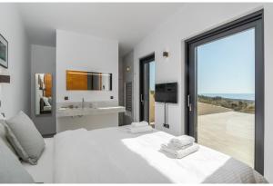 a bedroom with a white bed with a view of the ocean at Hourglass Villa's Milos in Psathadika