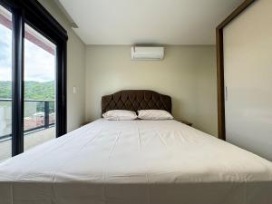 a bedroom with a large bed with a large window at Lindo apto com piscina em Bombas / SC in Bombas +42 photos