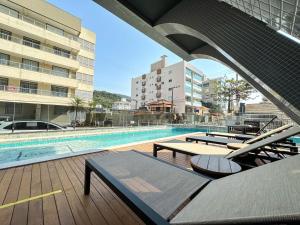 a swimming pool with chaise lounge chairs and a building at Lindo apto com piscina em Bombas / SC in Bombas