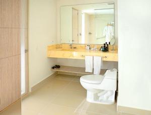 a bathroom with a toilet and a sink with a mirror at Sonesta Hotel Ibagué in Ibagué
