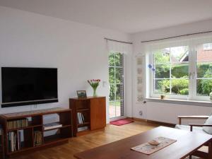 a living room with a flat screen tv and two windows at Holiday apartment with 2 bedrooms in Bad Zwischenahn