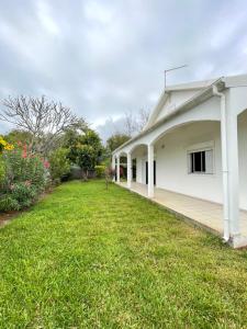 a white house with a grass yard at La Terrasse des Maldives in Saint-Paul