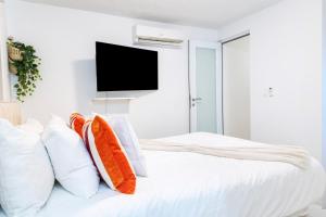 a white bedroom with a bed with pillows and a flat screen tv at Aquaville Dorado Moderna Villa 2 in Dorado