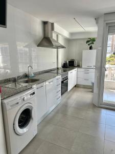 a white kitchen with a washing machine in it at Delmar Apartment in Alicante