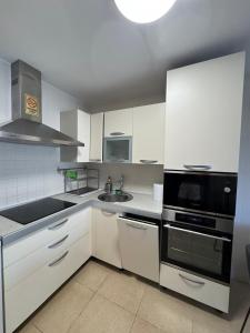 une cuisine avec des armoires blanches et un appareil noir dans l'établissement Premium Apartment in Palm Mar, à Palm-mar