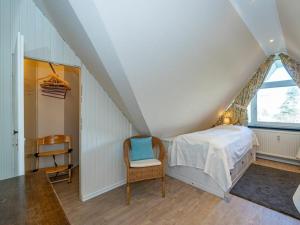 een slaapkamer met een bed en een stoel op zolder bij One-bedroom apartment in Wenningstedt