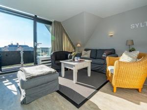 een woonkamer met een bank, stoelen en een tafel bij One-bedroom apartment in Wenningstedt