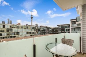 a balcony with a glass table and a view of the city at Beautiful 2BR - Pool, Gym & Parking Zodiak Stays in Auckland