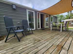 a deck with chairs and a table on a house at Mobil-home 5 personnes avec terrasse proche de la mer avec piscine et lagon in Vendres