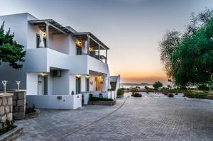 a white house with a sunset in the background at Agnanti View Hotel in Pachaina