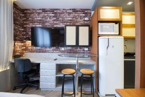 una cucina con bancone, frigorifero e sgabelli di Studio Silva Jardim - Próx Shop Estação com VAGA a Curitiba