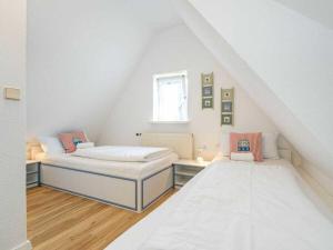 a attic room with two beds and a window at Island pearl in the Horsatal in Wenningstedt