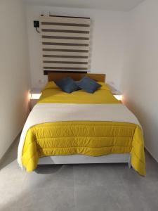 a bedroom with a yellow bed with two blue pillows at Raíces de Alcalá in Alcalá del Júcar