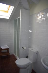 a white bathroom with a toilet and a sink at Pensión Arbidel in Ribadesella