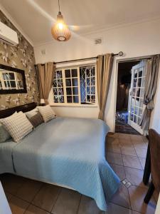 a bedroom with a blue bed and windows at Maple Tree Manor in Durban